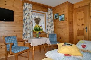 ein Wohnzimmer mit einem Tisch, Stühlen und einem TV in der Unterkunft Landhaus Maltermoos in Schönau am Königssee