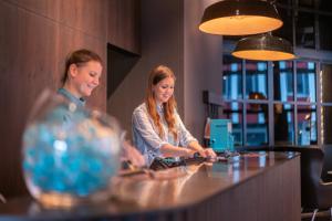 dwie kobiety siedzące przy ladzie w restauracji w obiekcie Motel One Berlin-Spittelmarkt w Berlinie