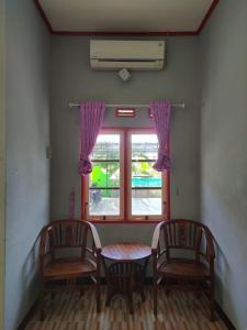 a dining room with two chairs and a table and a window at Adihan Homestay Mitra RedDoorz in Palangkaraya