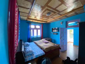 a bedroom with a bed with blue walls and a ceiling at Farmvilla Homestay in Kalpa
