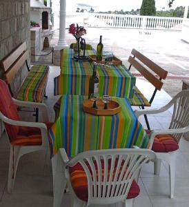 una mesa con un mantel colorido y botellas de vino en Apartments and Room Katja, en Mlini