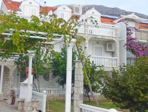 una casa blanca con columnas blancas y una valla en Apartments and Room Katja, en Mlini