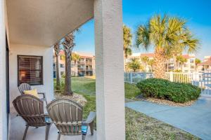 a porch with two chairs and palm trees at Driftwood Escape in Saint Augustine Beach