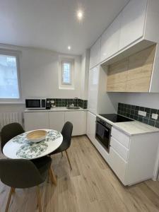 eine Küche mit einem Tisch, 2 Stühlen, einem Tisch und einer Theke in der Unterkunft Appartement cosy proche RER et centre ville in Le Plessis-Robinson