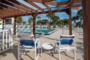 un patio con sillas, una mesa y una piscina en Driftwood Escape, en Butler Beach