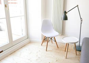 a living room with a white chair and a lamp at Haus Münsterblick in Reichenau