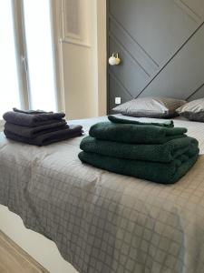 - un lit avec des serviettes vertes dans l'établissement Appartement cosy proche RER et centre ville, au Plessis-Robinson