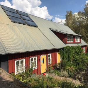 una casa roja y amarilla con paneles solares. en Klefstad Gård, en Linghem