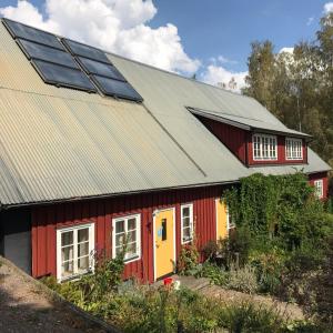 uma casa vermelha e amarela com painéis solares em Klefstad Gård em Linghem