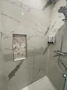La salle de bains en marbre est pourvue d'une douche et d'un lavabo. dans l'établissement Appartement cosy proche RER et centre ville, au Plessis-Robinson