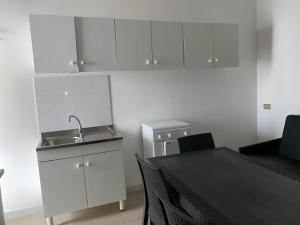 een keuken met witte kasten, een wastafel en een tafel bij Appartamenti - Spiaggia Zaiana in Peschici