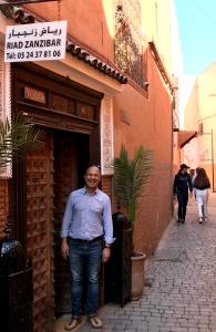 Um homem está em frente a um edifício. em Riad Zanzibar em Marrakech