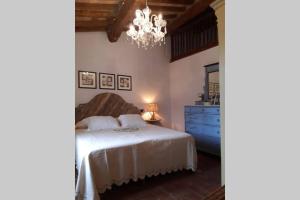 a bedroom with a bed with a blue dresser and a chandelier at Antiche Fonti in Bibbona