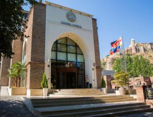 un edificio con escaleras delante con una montaña en el fondo en Tiflis Palace, en Tiflis