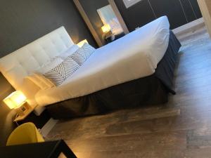 a large white bed in a room with a yellow chair at Hôtel de la Mer - Barcarès, à 100 m de la plage in Le Barcarès