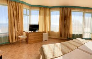 a bedroom with a bed and a tv and windows at Hotel Arabella Beach in Albena