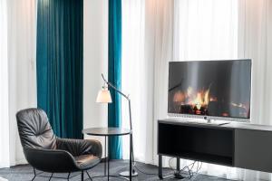ein Wohnzimmer mit einem TV und einem Stuhl in der Unterkunft Motel One Berlin-Upper West in Berlin