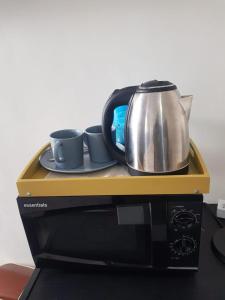 dzbanek do herbaty i dwie filiżanki na mikrofali w obiekcie izuba lodge w Kapsztadzie