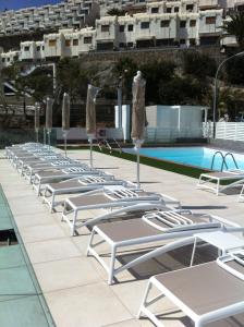 a row of lounge chairs next to a swimming pool at Puerto Príncipe in Puerto Rico de Gran Canaria