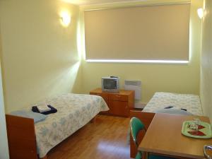 a room with two beds and a tv on a table at Kuressaare Airport Guest House in Kuressaare