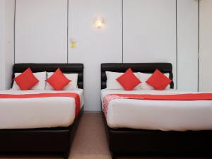 2 camas con almohadas rojas en una habitación en OYO 90180 Gemilang Hotel Kerteh, en Dungun