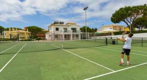 Ein Mann spielt Tennis auf einem Tennisplatz in der Unterkunft Villa w Private Pool, Tennis Courts & Golf Putt in Vilamoura