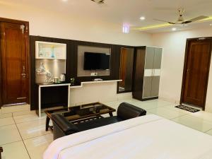a room with a bed and a tv and a couch at Mithilesh Hotel in Kaithal