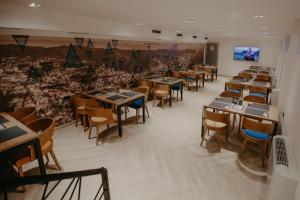 a dining room with tables and chairs and a tv at Hotel Vertigos in Tuzla