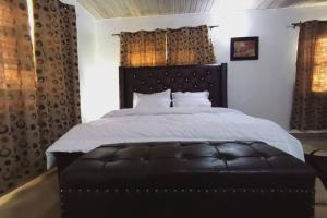 1 dormitorio con 1 cama grande y tabla de planchar de cuero negro en KALMS APARTMENT, en Port Harcourt