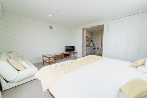 um quarto com uma cama branca e um sofá em Ecot Shimozato 2 em Miyako Island