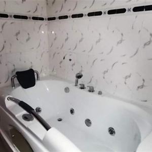 La salle de bains est pourvue d'une baignoire blanche et de murs en marbre. dans l'établissement Room in Lodge - Choice Suites 111 formerly Crown Cottage Hotel Ikeja, à Ikeja