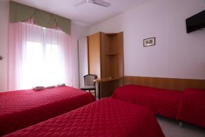 a bedroom with two red beds and a window at Hotel Picador in Rimini
