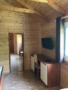 Cette chambre en bois comprend un bureau et une télévision. dans l'établissement The Mussel House, à Ksamil