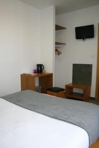 a bedroom with a bed and a tv and a chair at Hotel de la Gare in Mont-de-Marsan