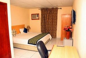 een hotelkamer met een bed, een tafel en een bureau bij Room in Lodge - Eaglespark1960 Hotel in Ikeja