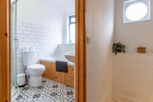 a bathroom with a toilet and a tub and a sink at The Shoe Box cottage with allocated parking in Malmesbury