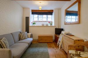 a living room with a couch and a television at The Shoe Box cottage with allocated parking in Malmesbury