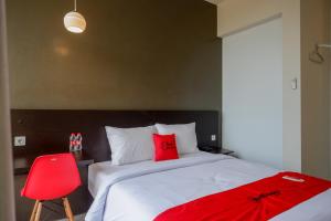 a bedroom with a bed with a red blanket on it at RedDoorz Plus near Solo Baru in Solo