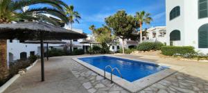 a swimming pool with an umbrella next to a building at Homenfun Menorca Playa de Fornells I in Fornells