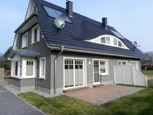 a house with a black roof and a white fence at Dünenperle in Zingst