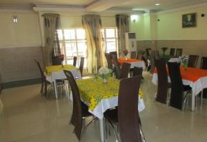 jadalnia ze stołami i krzesłami z żółtą i pomarańczową tkaniną w obiekcie Room in Lodge - Harlescourt Hotels and Suites Asaba w Asabie