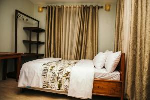 1 dormitorio con 1 cama con sábanas y almohadas blancas en Dual Mountain View Lodge, en Moshi
