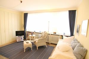 ein Wohnzimmer mit einem Sofa, Stühlen und einem TV in der Unterkunft Ferienwohnung Wilhelmine in Westerland