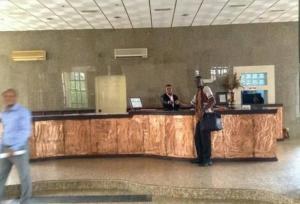 eine Person, die an einem Tresen in einer Lobby steht in der Unterkunft Room in Lodge - Nelrose Hotel, Asaba in Asaba