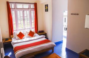 Zimmer mit einem Bett mit orangefarbenen Kissen und einem Fenster in der Unterkunft Dungmali Heritage Resort in Namchi