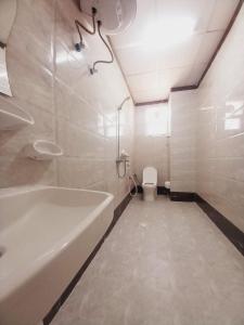 a bathroom with a tub and a toilet and a sink at Discovery Duqm Apartment in Duqm