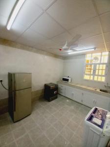 an empty kitchen with a refrigerator in a room at Discovery Duqm Apartment in Duqm