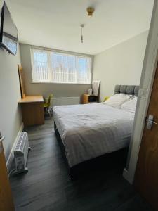 a bedroom with a bed and a desk and a window at Cranmore Guest House in Solihull