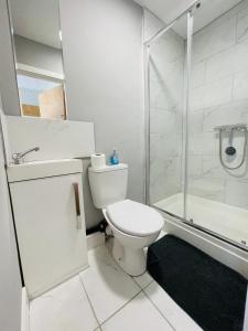 a white bathroom with a toilet and a shower at Cranmore Guest House in Solihull