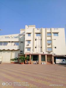 a large white building with a courtyard in front of it at Vamoose Sujata Residency in Sundargarh